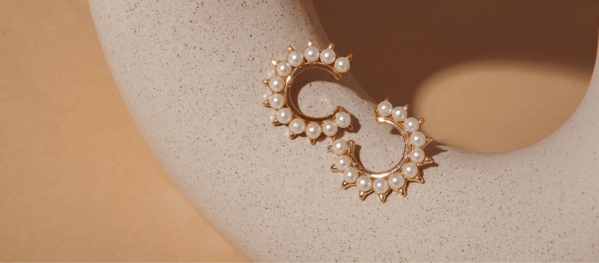Gold and pearl VILIA earrings on a sculptural display